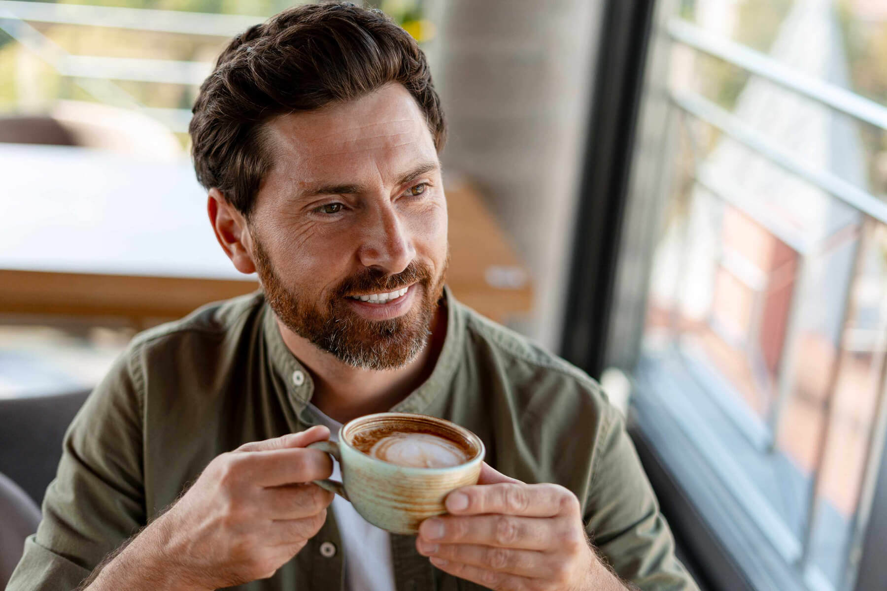 happy-businessman-drinking-cappuccino-and-looking--TTM4S9T